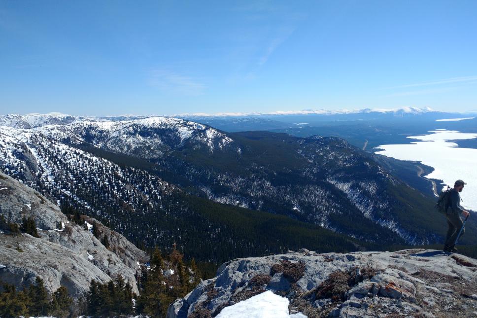 man hiking on top of a mountain with a lake down below