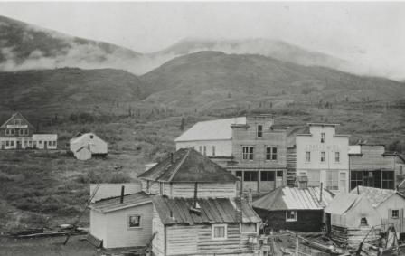 black and white photo of historic buildings with mountains in the background