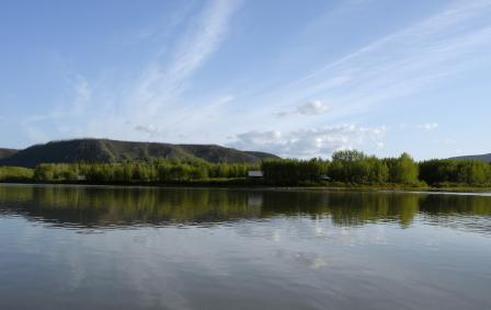 A horizon shot with water in the foreground, sky above, and mountainous land in the middle.