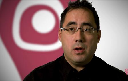 Indigenous man wearing glasses and black button down shirt.