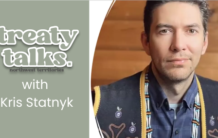 Kris Statnyk wearing a dark blue vest with yellow trim and embroidery and beading with Treaty Talks NWT logo