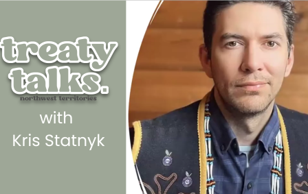 Kris Statnyk wearing a dark blue vest with yellow trim and embroidery and beading with Treaty Talks NWT logo